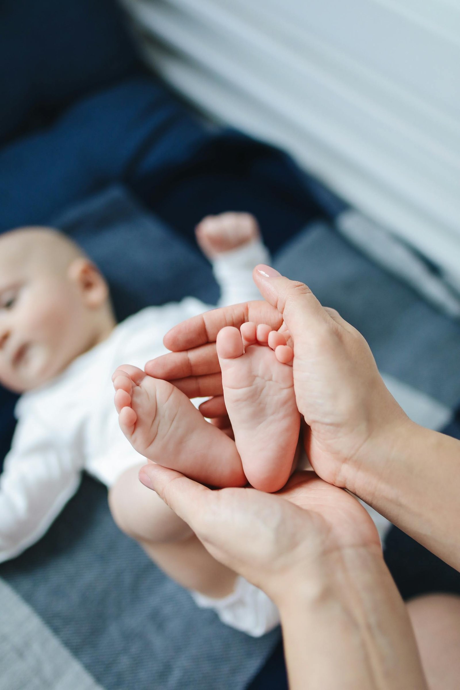 A close-up of parent holding baby feet, capturing a tender moment of affection indoors.